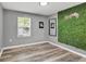 Modern bedroom with plank floors, a grass accent wall, and a window with natural light at 955 Chandler Haulk Rd, Loganville, GA 30052