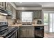 Open kitchen featuring a double basin sink, tile backsplash, black appliances, and access to an outdoor deck at 955 Chandler Haulk Rd, Loganville, GA 30052