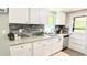 Bright kitchen with white cabinetry, gray backsplash, stainless steel appliances, and granite countertops at 272 Old Sudie Rd, Hiram, GA 30141