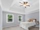 A cozy bedroom with a tray ceiling, a ceiling fan, two windows, and neutral decor at 4605 Tims Pl, Snellville, GA 30039