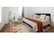 Bright bedroom featuring hardwood floors, modern rug, and adjacent hallway with stairs at 135 Mado Ln, Chattahoochee Hills, GA 30268