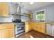 Well-lit kitchen with wooden cabinets, granite countertops, stainless steel appliances, and a modern vent hood at 2024 Lower Burris Road Rd, Canton, GA 30114
