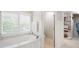 Bathroom featuring a soaking tub next to shuttered windows and a door to a walk-in closet at 3361 Woodington Se Ct, Marietta, GA 30067