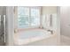 Bright bathroom showcasing a soaking tub with shuttered windows and elegant white paneling at 3361 Woodington Se Ct, Marietta, GA 30067