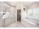 Large bathroom displays custom cabinets, a walk-in shower, and a soaking tub with shuttered window at 3361 Woodington Se Ct, Marietta, GA 30067