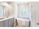 Bathroom with gray vanity, modern fixtures, a freestanding tub, and a window at 3810 Jack Vernon Cir, Powder Springs, GA 30127