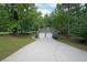 Detached two-car garage is shown from the driveway surrounded by mature trees and green lawns at 5807 Christopher Ln, Lithonia, GA 30058