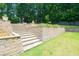 Tiered stone retaining wall featuring stairs and planters in a large backyard with trees at 9701 Buice Rd, Alpharetta, GA 30022