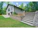 Back view of a brick home featuring a large patio, stone steps, and lush landscaping at 9701 Buice Rd, Alpharetta, GA 30022
