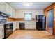 A kitchen with wood paneling, linoleum flooring, white cabinets, and black appliances at 2201 Bollingbrook Drive, Atlanta, GA 30311