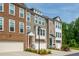 View of townhomes with attached garages, varied brick and siding, manicured landscaping, and colorful front doors at 996 Layton Dr, Buford, GA 30518