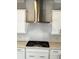 Well-equipped kitchen featuring tile backsplash, stainless steel range hood, and white cabinetry at 996 Layton Dr, Buford, GA 30518