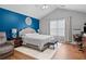 Vaulted ceiling bedroom featuring a king bed, wood floors, and a serene blue accent wall at 1047 Woodsong Pass Ct, Lawrenceville, GA 30043