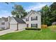 Charming two-story home featuring a well-manicured lawn, attached garage, and a vibrant red front door at 1047 Woodsong Pass Ct, Lawrenceville, GA 30043