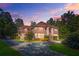 A grand brick home at twilight with manicured front lawn and long driveway at 7523 Kimberly Lynn Ct, Lithonia, GA 30058