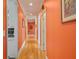 Hallway with hardwood floors and bright orange walls leading to multiple rooms at 7523 Kimberly Lynn Ct, Lithonia, GA 30058
