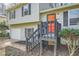 This home features an inviting front entrance with gray steps, an orange door, and muted green siding at 840 Wells Se Cir, Smyrna, GA 30080