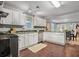 Well-lit kitchen featuring white cabinets, stainless steel appliances, and an adjacent dining area at 1311 Sylvan Cir, Brookhaven, GA 30319