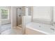 Bathroom featuring a tub, tiled shower, and serene lighting for a spa-like experience at 1537 Maplecliff Way, Sugar Hill, GA 30518