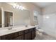 Bright bathroom with double sinks, dark vanity, and shower with a tub at 1537 Maplecliff Way, Sugar Hill, GA 30518