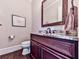 Powder room features a dark vanity, attractive mirror and hardwood floors at 5039 Towne Lake Hills North, Woodstock, GA 30189