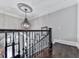 Upstairs hallway with dark wood floors, black iron railing, and a decorative ceiling medallion at 5039 Towne Lake Hills North, Woodstock, GA 30189