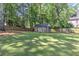 Spacious backyard with mature trees, a lush lawn, and a charming shed along a wooden fence at 125 Foxridge Rd, Atlanta, GA 30327