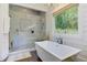 Bright bathroom featuring a modern tub, glass-enclosed shower, and a scenic window at 125 Foxridge Rd, Atlanta, GA 30327