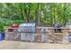 Spacious outdoor kitchen with stainless steel appliances, stone surround, and lush greenery at 125 Foxridge Rd, Atlanta, GA 30327