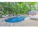 Beautiful backyard pool with lush greenery, poolside seating, and a covered outdoor kitchen and dining area at 125 Foxridge Rd, Atlanta, GA 30327