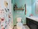 Inviting bathroom with floral shower curtain, vanity, and aqua colored walls at 3769 Bay Creek Church Rd, Loganville, GA 30052