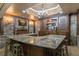 Basement bar area featuring a stone backsplash, bar seating, custom cabinetry, and elegant lighting at 8970 Moor Park Run, Duluth, GA 30097