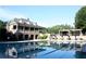 Community pool with clubhouse in the background featuring stone architecture, pool furniture, and pergola at 8970 Moor Park Run, Duluth, GA 30097