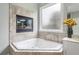 Corner soaking tub with tiled surround and frosted glass window at 5365 Glenhaven Dr, Cumming, GA 30041