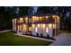 Exterior home at dusk showing professional lighting, white brick, wood accents, three-car garage and green lawn at 942 Fairfield, Marietta, GA 30068