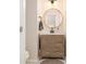 Stylish half bathroom featuring a wooden vanity, round mirror, modern lighting fixture, and a neutral color palette at 1031 Bailey Rd, Woodstock, GA 30188