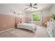 Charming bedroom with pink accent wall, a cozy brass bed, a ceiling fan, and plenty of natural light from the window at 1031 Bailey Rd, Woodstock, GA 30188