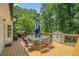 Wooden deck with outdoor dining table and umbrella, surrounded by lush greenery for relaxing outdoor meals at 1031 Bailey Rd, Woodstock, GA 30188