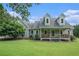 Charming two-story home with a welcoming front porch and lush green lawn on a sunny day at 225 W Union Grove Cir, Auburn, GA 30011
