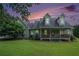 Charming two-story home with a welcoming front porch and lush green lawn at sunset at 225 W Union Grove Cir, Auburn, GA 30011