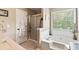 Bright bathroom featuring a soaking tub, glass door shower, and neutral finishes at 242 Sandhurst Ct, Suwanee, GA 30024
