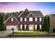 Charming two-story brick home with a manicured lawn and inviting curb appeal during a lovely sunset at 242 Sandhurst Ct, Suwanee, GA 30024