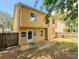 Yellow home has door to the fenced backyard with overgrown grass and some trees at 2918 Pavia Circle, Austell, GA 30106