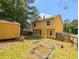 Yellow home has fenced backyard with storage shed, garden boxes, and partially overgrown grass at 2918 Pavia Circle, Austell, GA 30106