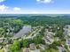 Expansive aerial view of a neighborhood with a lake, lush trees, and well-maintained homes under a blue sky at 4955 Winding Rose Dr, Suwanee, GA 30024