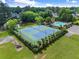 Aerial view of tennis courts and swimming pool with mature trees, a lake view and manicured grounds at 4955 Winding Rose Dr, Suwanee, GA 30024