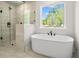 Bright bathroom featuring a modern soaking tub and glass-enclosed shower with black fixtures and a picturesque window view at 910 Melody Ridge Ln, Buford, GA 30518