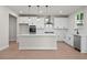 Modern white kitchen featuring a large island, stainless steel appliances, and stylish pendant lighting at 910 Melody Ridge Ln, Buford, GA 30518