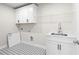 Functional laundry room with ample white cabinetry, a utility sink, and modern patterned flooring at 910 Melody Ridge Ln, Buford, GA 30518