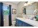 Stylish bathroom featuring blue vanity with white countertop, gold mirror, and window with dark curtains at 177 Coopers Pond Dr, Lawrenceville, GA 30044